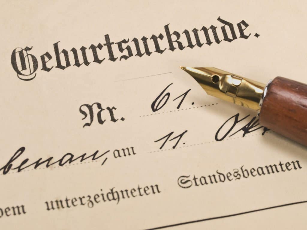 Ausschnitt einer historischen Geburtsurkunde mit handschriftlichen Einträgen und einem Füllfederhalter
