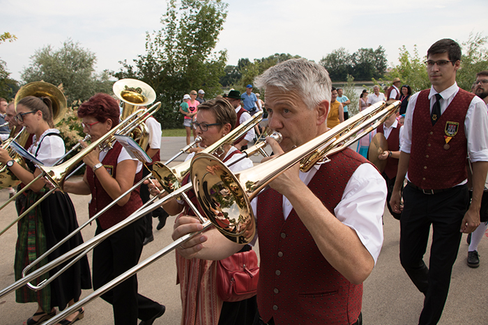 Donaufest 2019: Blaskapelle beim Festumzug Musikerinnen und Musiker einer Blaskapelle spielen während des Donaufests 2019 auf Posaunen und weiteren Blechblasinstrumenten in einem Festumzug.