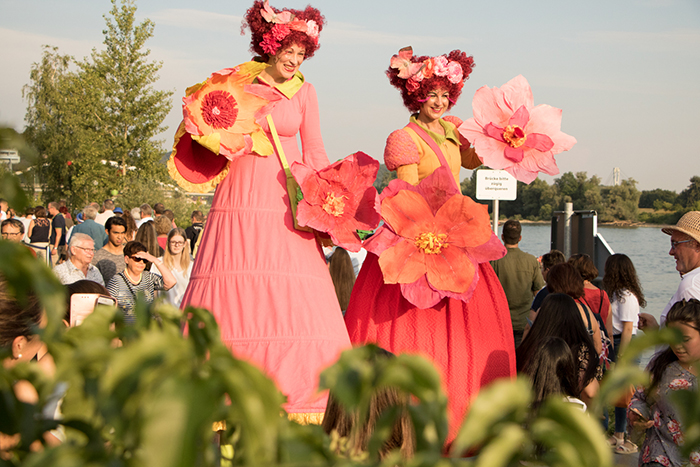 Donaufest 2019: Blumenfiguren beim Festumzug Drei kostümierte Personen mit großen rosa Blumen vor einem Publikum im Freien