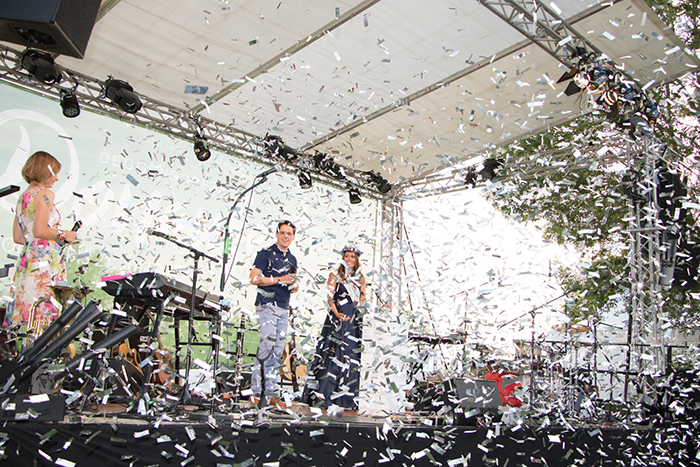 Donaufest 2019: Bühnenauftritt im Konfettiregen Drei Personen stehen auf einer überdachten Bühne, während Konfetti durch die Luft fliegt; links sind ein Keyboard und weitere Bühnentechnik zu sehen.