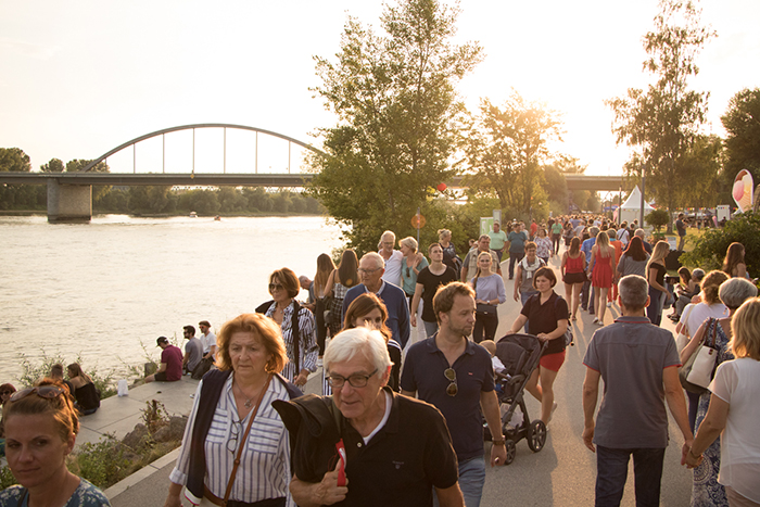 Donaufest 2019 an der Donau in Deggendorf Viele Menschen spazieren bei sommerlichem Wetter am Donauufer entlang; im Hintergrund sind eine Brücke, Bäume und die Donau zu sehen.