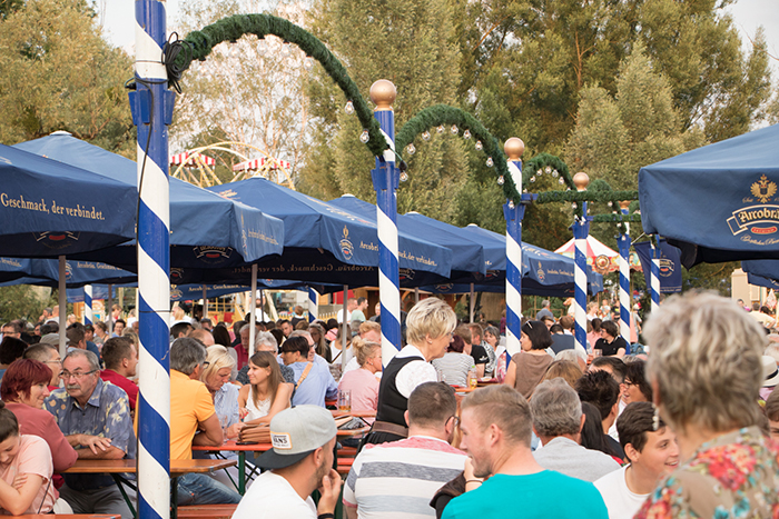 Donaufest 2019 in Deggendorf: Festzelt mit Besucherinnen und Besuchern Dicht besetzter Festbereich mit blau-weißen Zelten, geschmückten Maibäumen und zahlreichen Besucherinnen und Besuchern beim Donaufest 2019 in Deggendorf.