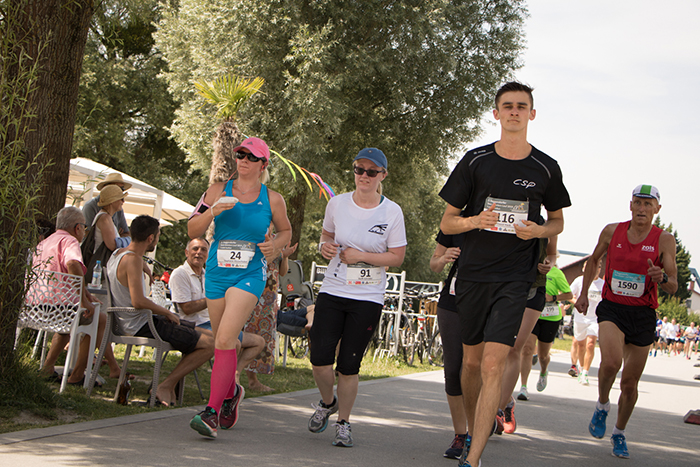 Donaufest 2019: Läuferinnen und Läufer beim Straßenlauf Mehrere Läuferinnen und Läufer mit Startnummern auf einer asphaltierten Strecke unter Bäumen; am Rand stehen Zuschauerinnen und Zuschauer.