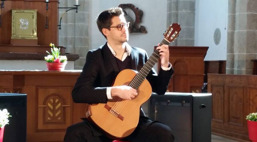 Gitarrist bei einer musikalischen Veranstaltung in der Kirche Ein Gitarrist spielt auf einer klassischen Gitarre in einer Kirche.