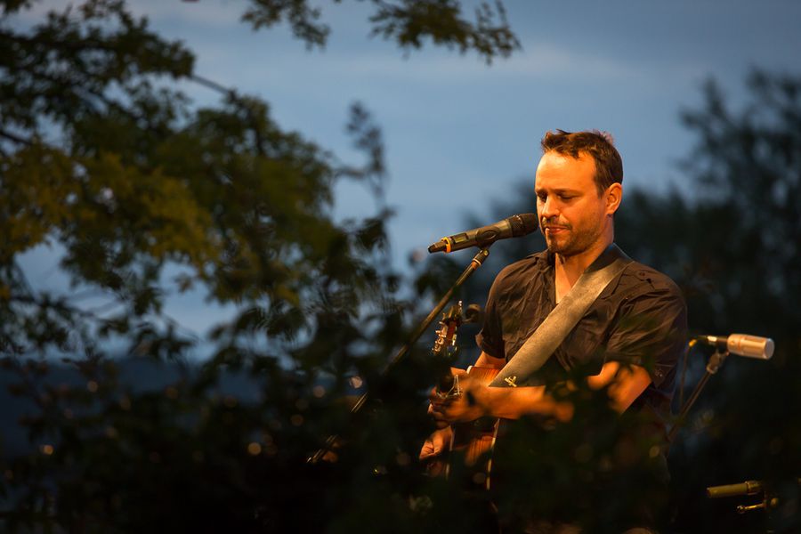 Musiker beim Auftritt im Freien Musiker mit Gitarre und Mikrofon bei einem Auftritt im Freien