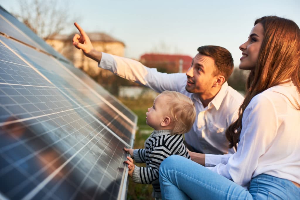 Photovoltaikanlage im Familienalltag Eine Familie betrachtet im Freien eine aufgestellte Photovoltaikanlage; ein Mann zeigt auf die Solarmodule.
