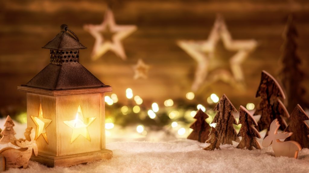 Beleuchtete Laterne mit Sternmotiven, Holzsternen und dekorativen Tannenbäumen in weihnachtlicher Szene