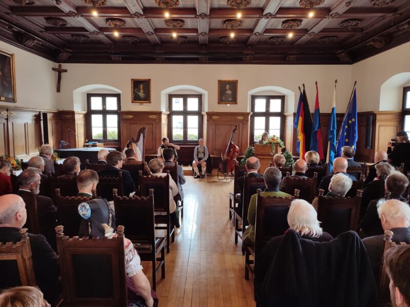 Veranstaltung im Alten Rathaus Deggendorf Festliche Veranstaltung mit zahlreichen Gästen im historischen Sitzungssaal des Alten Rathauses in Deggendorf; an der rechten Seite stehen mehrere Fahnen.