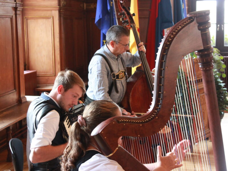 Musiker mit Kontrabass und Harfe bei einer Veranstaltung Zwei Musiker spielen Kontrabass und Harfe, während eine weitere Person an der Harfe sitzt.