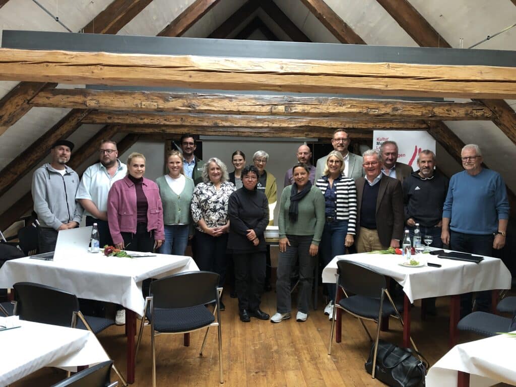 Gruppenfoto des Touri-Gipfeltreffens 2026 in Bischofsmais mit mehreren Erwachsenen in einem rustikalen Veranstaltungsraum