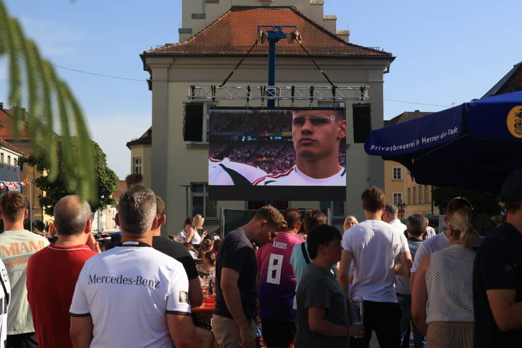 Public Viewing zur Handball-WM auf dem Deggendorfer Stadtplatz Menschen verfolgen bei einer öffentlichen Übertragung auf dem Deggendorfer Stadtplatz ein Handballspiel auf einer großen Leinwand.