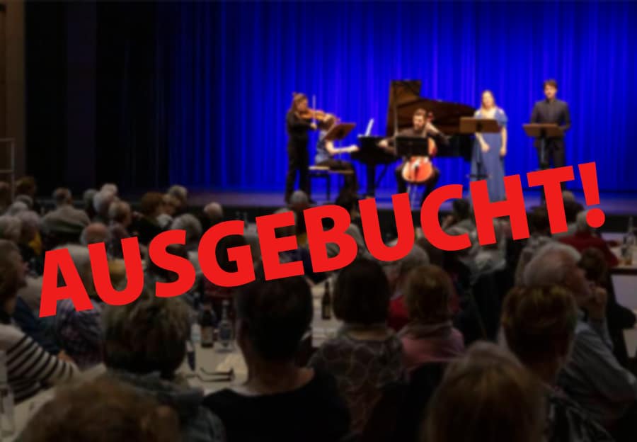 Ein Konzertensemble musiziert auf einer blau beleuchteten Bühne vor dicht besetzten Zuschauerreihen; der rote Schriftzug „AUSGEBUCHT!“ liegt über dem Bild.