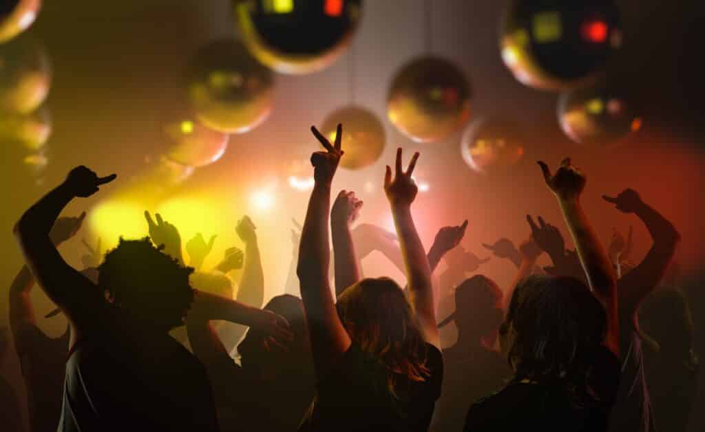 Eiszeit-Special: Discolauf mit Party-Hits im Eisstadion Deggendorf Feiernde Menschen mit erhobenen Armen und Luftballons bei einer farbig beleuchteten Partyveranstaltung