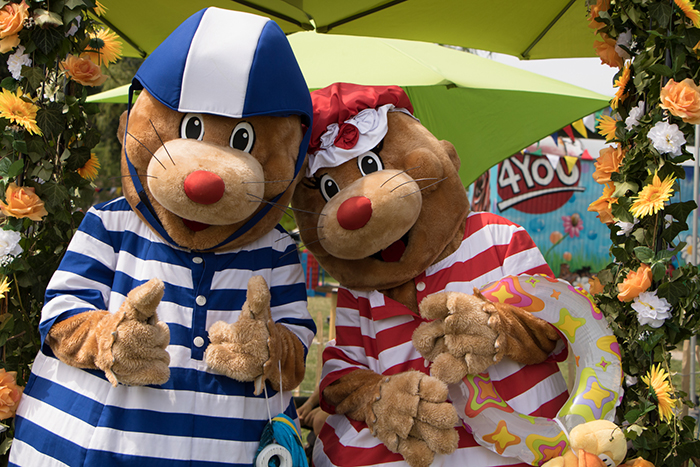 Donaufest 2019: Maskottchen im Matrosenlook Zwei verkleidete Maskottchen in blau-weißem und rot-weißem Matrosenlook stehen unter einem grünen Sonnenschirm und posieren zwischen Blumenschmuck.