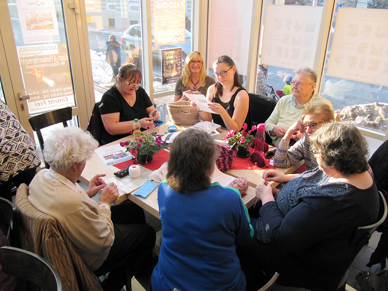 Mehrere Frauen sitzen bei einem Stricktreffen an einem Tisch im Handwerksmuseum und arbeiten mit Wolle und Nadeln.