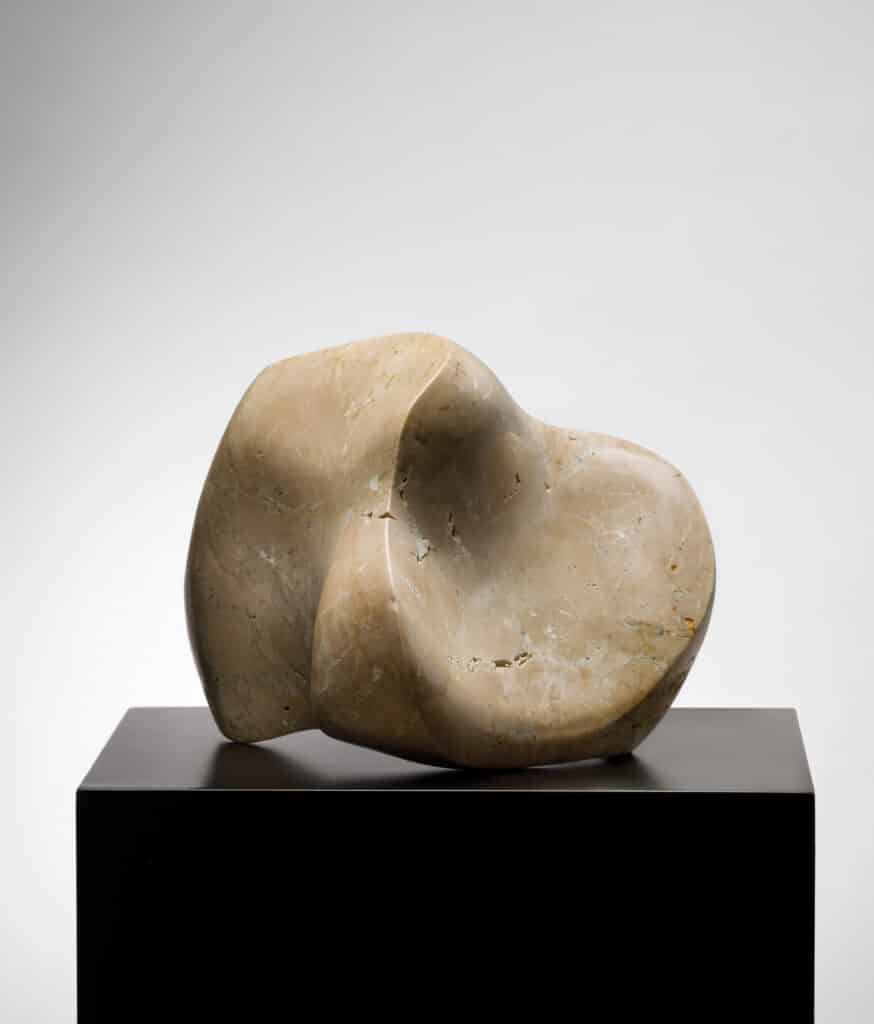 Abstrakte helle Steinskulptur auf einem schwarzen Sockel vor neutralem Hintergrund