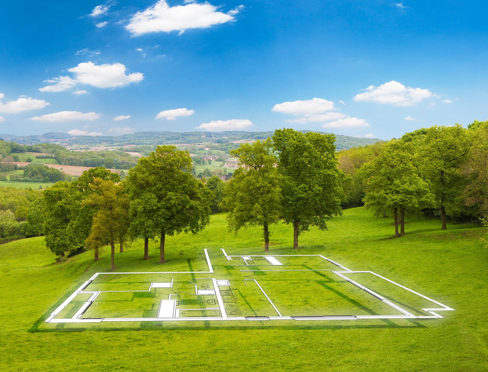 Markierte Baufläche auf einer grünen Wiese mit Bäumen und Blick über die Landschaft