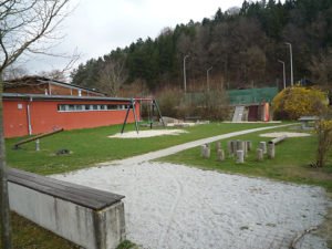 Grünfläche mit rotem Vereinsgebäude, Schaukel, Klettergerüst und Sitzgelegenheiten an der Kunertstraße