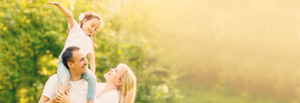 Eltern und Kind verbringen gemeinsam einen sonnigen Sommertag im Grünen.