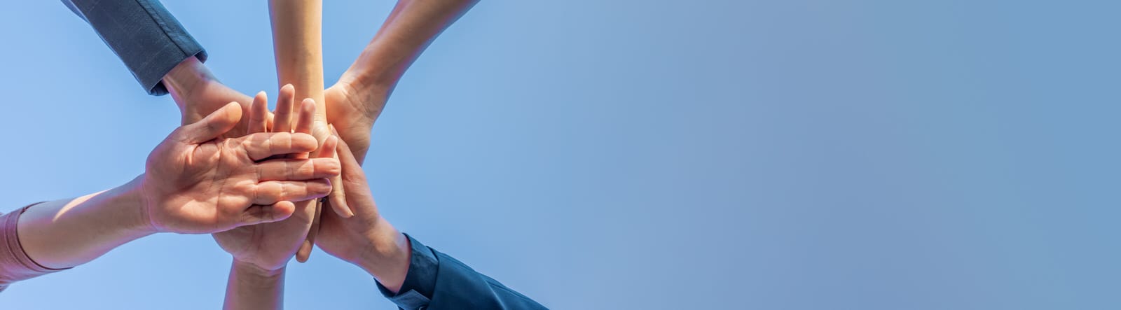 Gemeinsam engagiert im Verein Mehrere Menschen legen ihre Hände übereinander und bilden ein Zeichen des Zusammenhalts unter freiem Himmel.