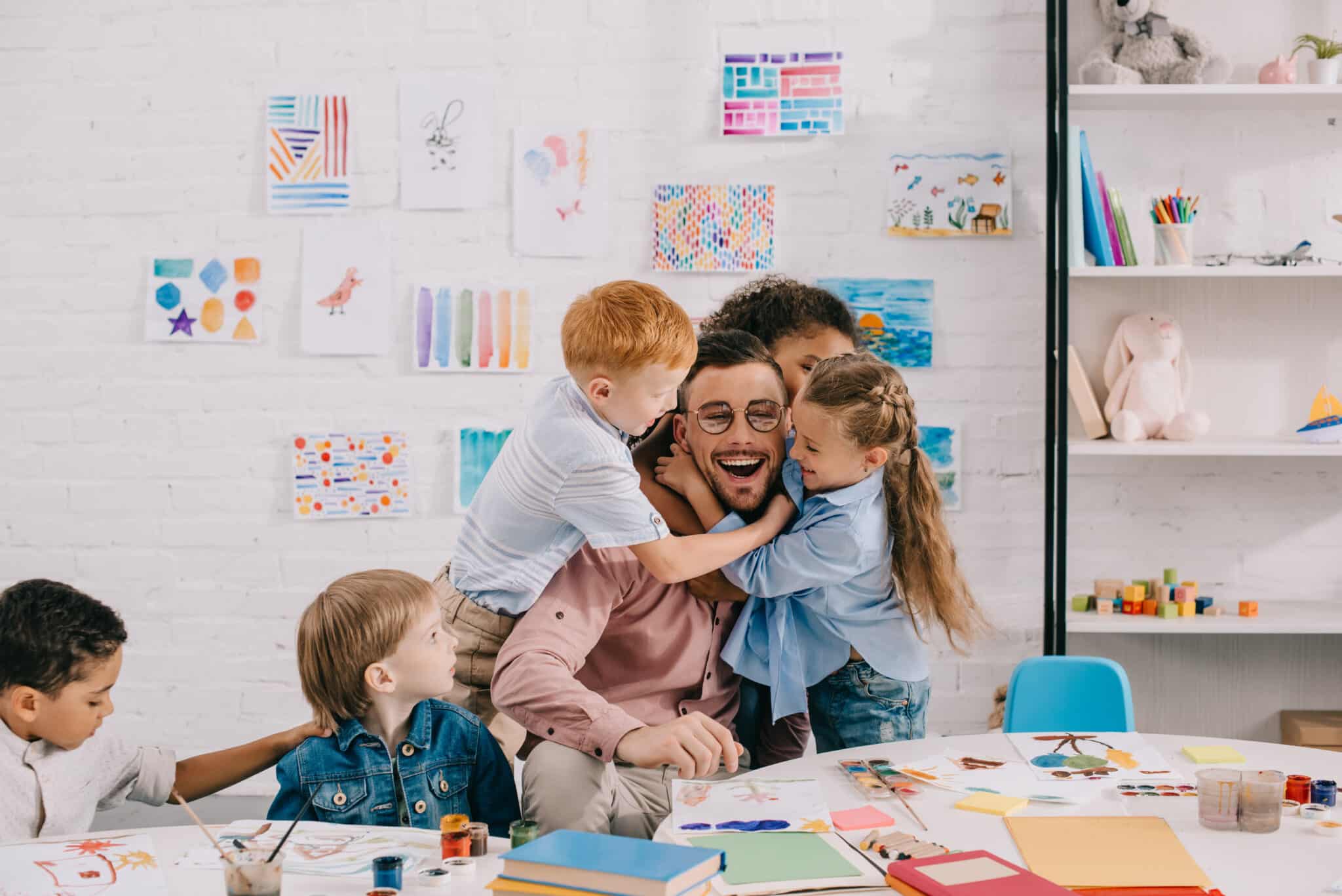 Familie beim gemeinsamen Basteln mit Kindern Erwachsene Person und drei Kinder basteln und malen gemeinsam an einem Tisch in einem hellen Kreativraum.