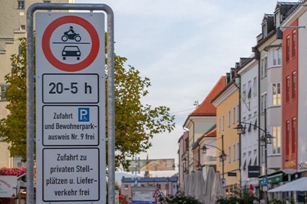 Verkehrsschild mit Zufahrtsbeschränkung von 20 bis 5 Uhr sowie Hinweis auf Bewohnerparkausweise und private Stellplätze vor einer innerstädtischen Häuserzeile.