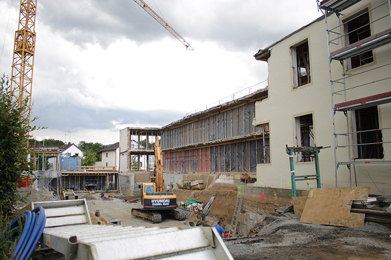 Baustelle mit Neubauten, Baukran, Gerüst und Baufahrzeugen unter bewölktem Himmel