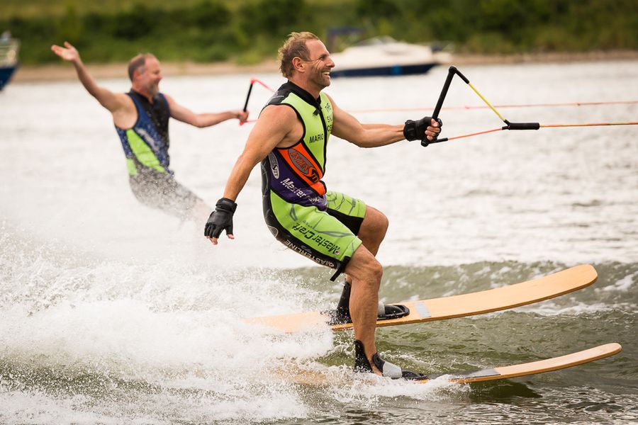 Kitesurf-Show beim Vereinssportfest in Deggendorf 2015 Zwei Kitesurfer fahren bei einer Sportveranstaltung über das Wasser; der vordere Sportler trägt ein buntes Trikot und hält eine Kite-Steuerstange.