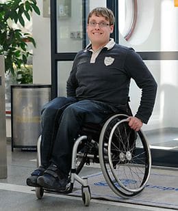 Sebastian Schraufstetter sitzt in einem Rollstuhl in einem hellen Innenraum.