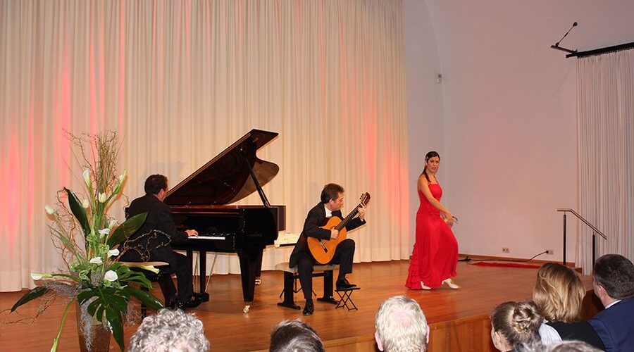Konzert mit Sängerin, Pianist und Gitarrist Sängerin in rotem Kleid, Pianist und Gitarrist bei einem Konzert auf einer Bühne vor Publikum