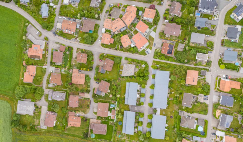 Luftaufnahme eines bebauten Wohngebiets mit Einfamilienhäusern, Straßen, Gärten und landwirtschaftlichen Flächen am Ortsrand von Deggendorf.