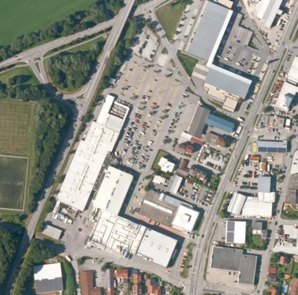 Luftaufnahme eines Gewerbegebiets in Deggendorf mit großen Hallen, Parkplätzen, Straßen und einer Anschlussstelle