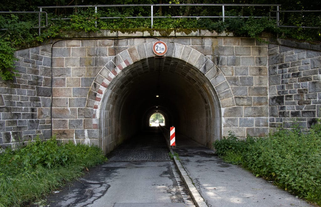 Gemauerte Eisenbahnunterführung mit geöffnetem Tunnelportal, Höhenbegrenzung und Leitbake in Deggendorf