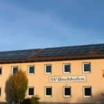 Gelbes Vereinsgebäude des SV Buchhofen mit dem Vereinsnamen an der Fassade, Wappen und Solaranlage auf dem Dach