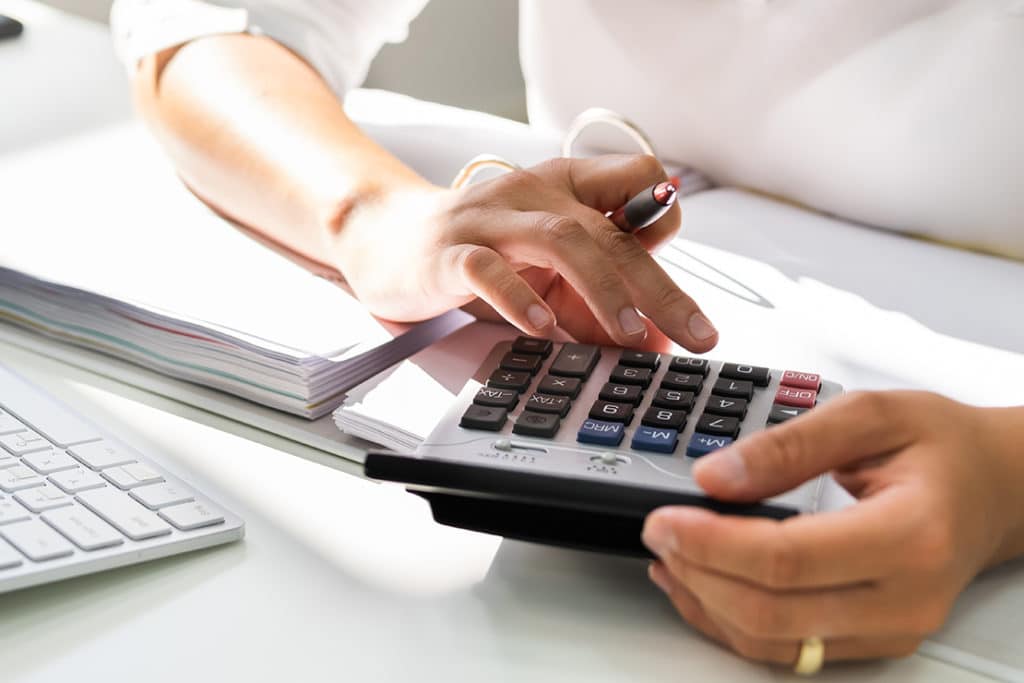 Verein, Ort und Veranstaltung in der Saison 2020 – Finanzplanung Hände bedienen einen Taschenrechner neben Unterlagen und einer Tastatur auf einem Schreibtisch.