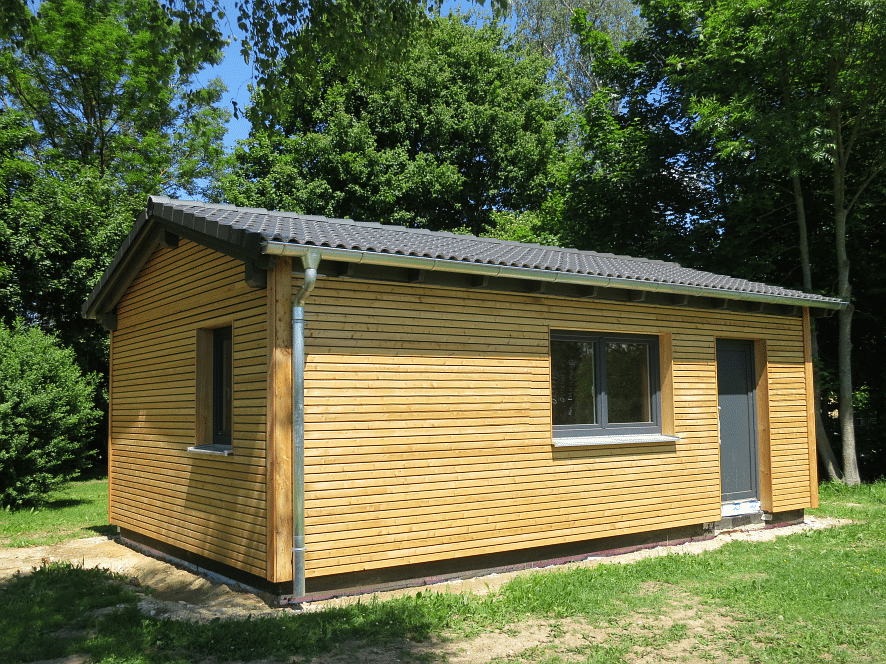 Holzgebäude eines Waldkindergartens auf einer Wiese am Waldrand