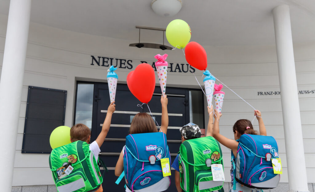 Schulranzen-Aktion vor dem Neuen Rathaus Vier Kinder mit bunten Schulranzen halten Schultüten und Luftballons vor dem Neuen Rathaus.