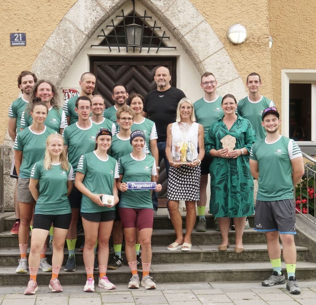 Lauf-KulTour 2024 in Deggendorf Gruppenfoto eines Laufteams und weiterer Beteiligter vor dem Eingang eines Gebäudes in Deggendorf; mehrere Personen tragen grüne Laufshirts.