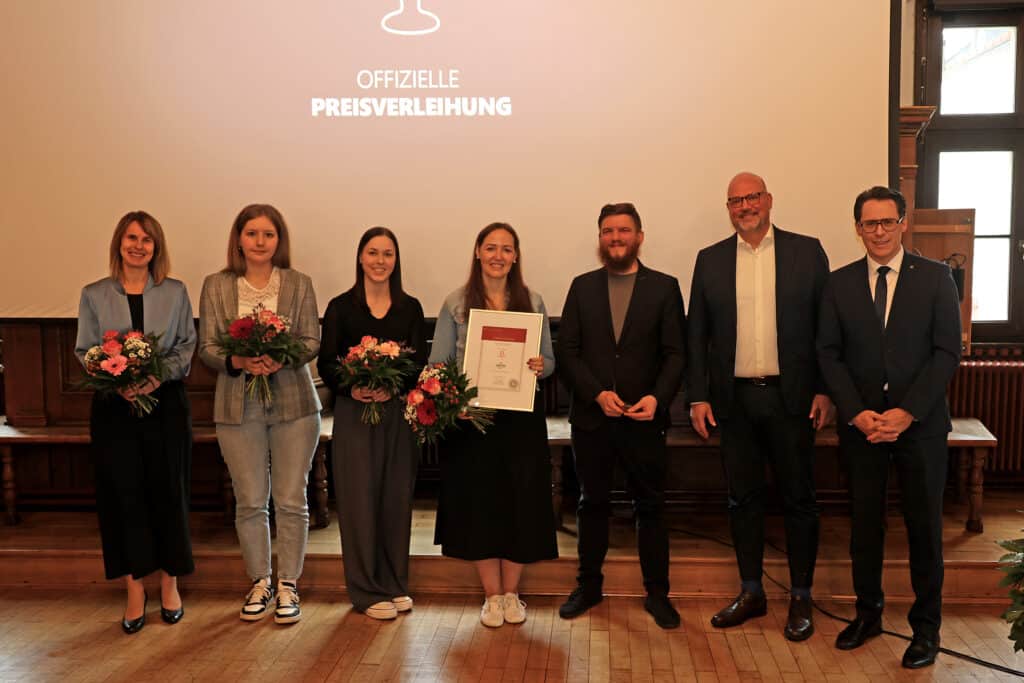 Ausbildungsförderpreis 2024 – Preisverleihung Gruppenfoto mit sechs Frauen und drei Männern bei der offiziellen Preisverleihung; eine Frau hält eine gerahmte Urkunde, mehrere Personen halten Blumensträuße.