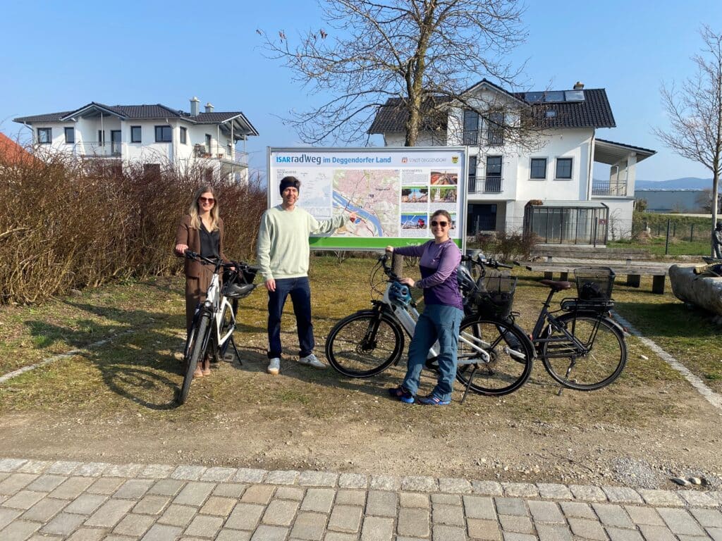Start des Isarradwegs in Deggendorf Drei Personen stehen mit Fahrrädern vor einer Infotafel zum Isarradweg in Deggendorf.