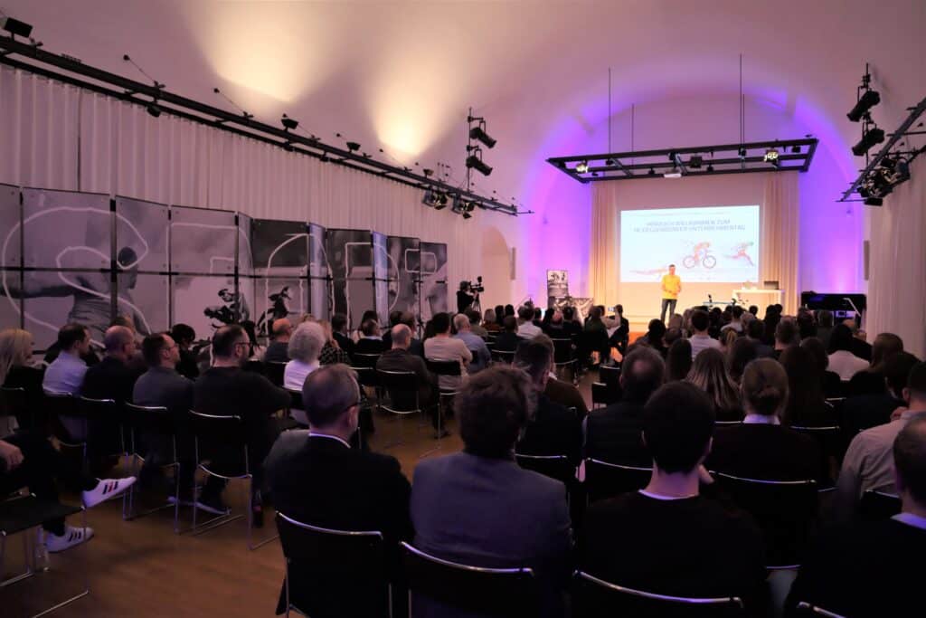 Publikum verfolgt einen Vortrag beim Unternehmertag in Deggendorf 2024 in einem Veranstaltungssaal.