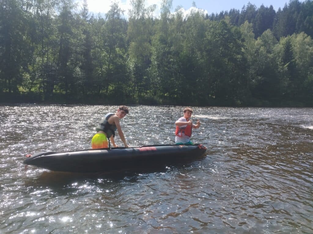 4You-Paddeln auf der Isar 2025 Zwei Personen paddeln in einem Schlauchboot auf der Isar; im Hintergrund ist ein bewaldetes Ufer zu sehen.