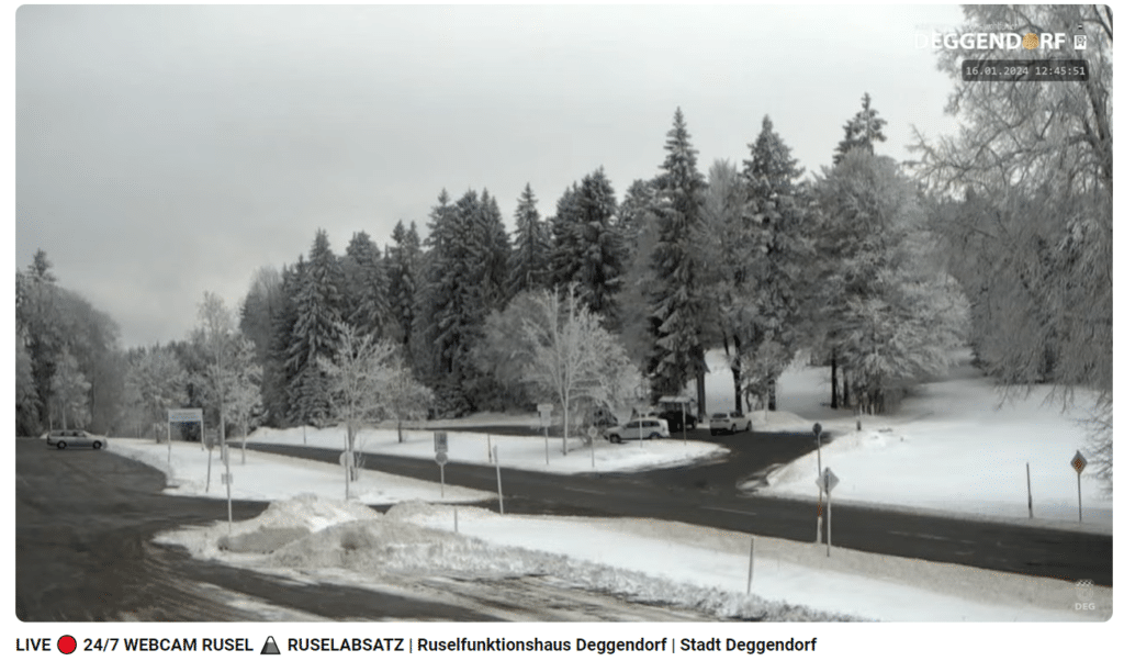 Webcam Rusel im Winter Verschneite Straßenkreuzung mit verschneitem Wald und einzelnen Fahrzeugen an der Rusel bei Deggendorf.