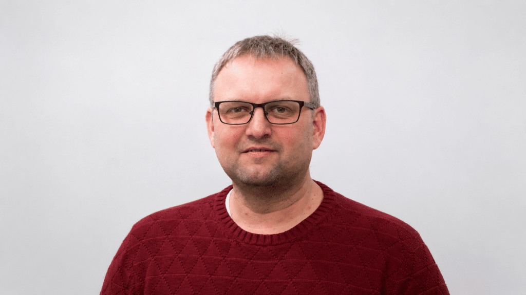 Porträt eines Mannes mit Brille und dunkelrotem Pullover Porträt eines Mannes mit Brille und dunkelrotem Pullover vor hellem Hintergrund