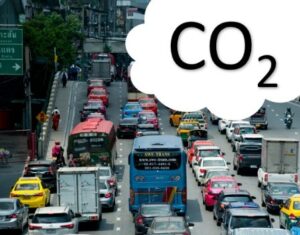 Dichter Stadtverkehr mit Bussen, Autos, Lastwagen und Motorrädern; darüber steht groß CO₂.