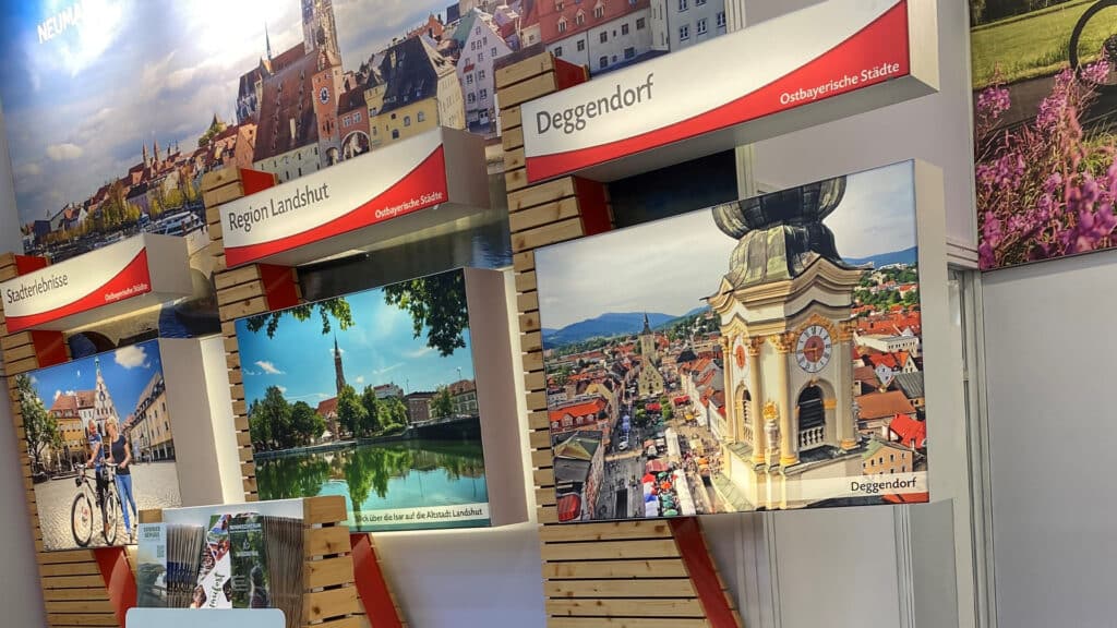 Messestand mit großformatigen Bildern von Deggendorf, darunter die Stadtansicht mit dem Grabkirchturm, die Donau und historische Gebäude