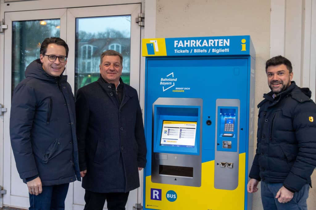 Vorstellung eines Fahrkartenautomaten am Bahnhof Deggendorf Drei Männer stehen neben einem blau-gelben Fahrkartenautomaten in einem Bahnhofsgebäude; am Automaten steht „FAHRKARTEN“ sowie „Tickets / Billets / Biglietti“.
