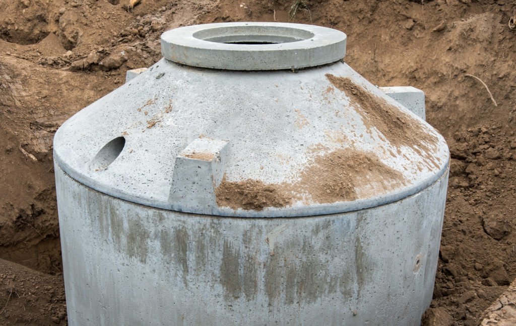 Runder Betonbehälter einer Kleinkläranlage in einer Baugrube