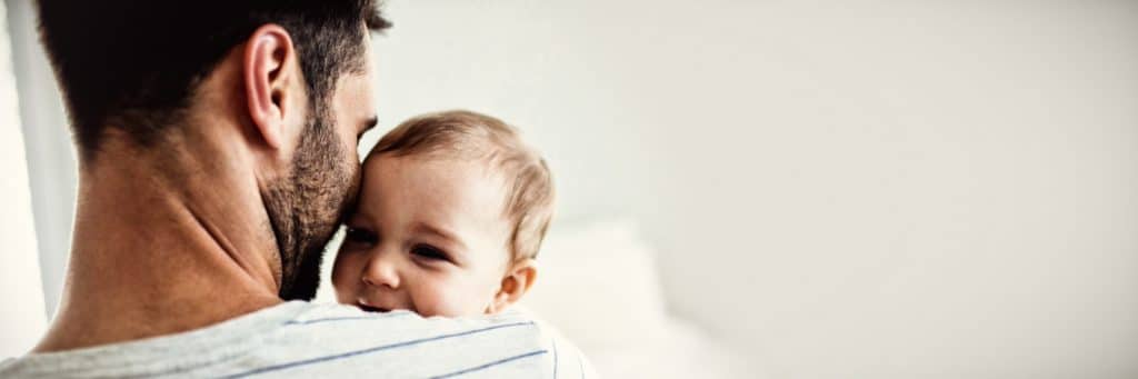 Vater hält ein Baby liebevoll im Arm