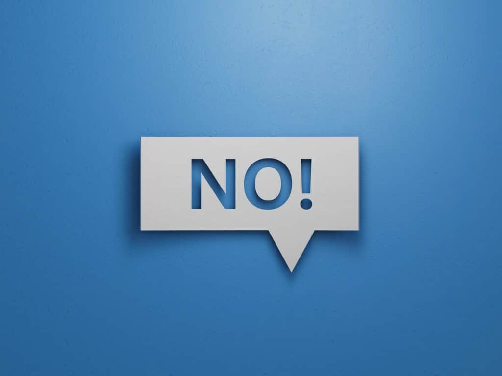 Weißes Sprechblasen-Schild mit dem Wort „NO!“ vor blauem Hintergrund